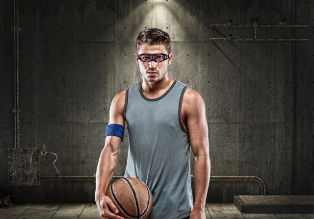 young man on dark background holding basketball ball